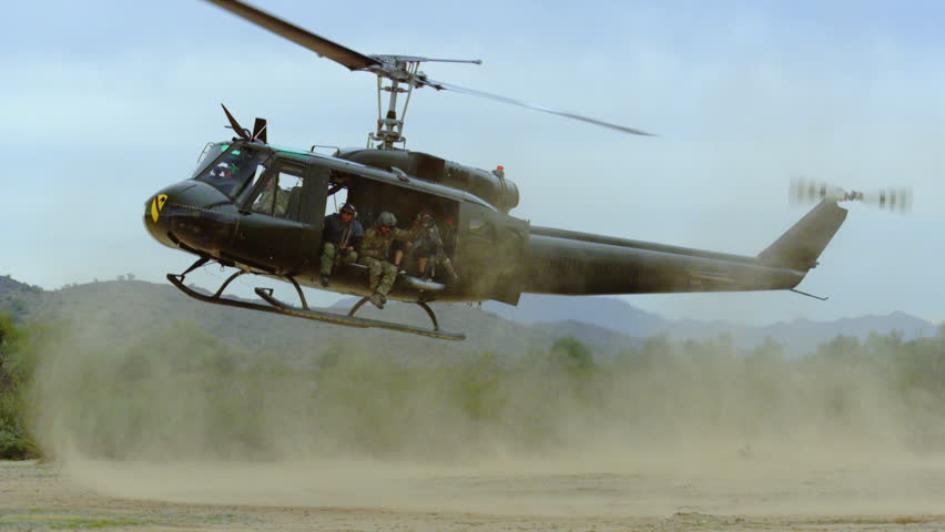 Huey helicopter lands in the desert, slow motion.