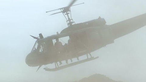 Huey helicopter taking off, with riders, the desert