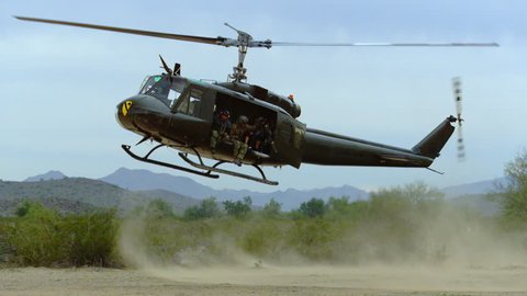 Huey helicopter flies and lands in the desert.