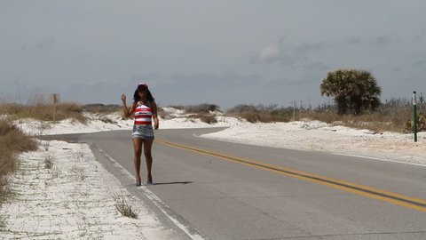 Colorfully dressed black woman runs down a deserted road in shorts and blue high heeled shoes.