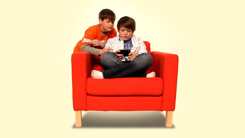 Two young boys play a handheld video game.