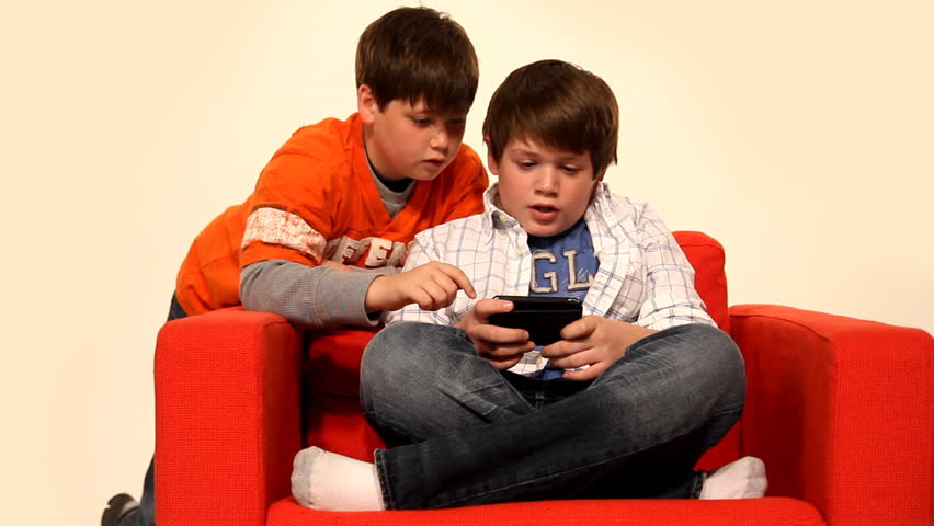 Two young boys play a handheld video game.