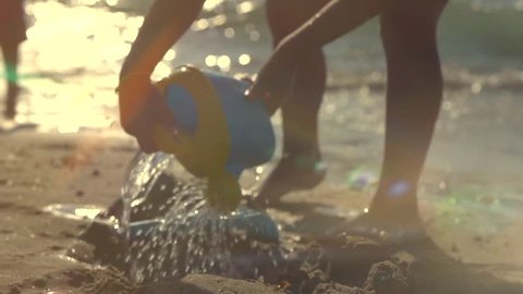 A Little Girl Having Fun with a Sand and Sear water. Silhouette of a Child Playing with Toys on the Seashore. Funny little girl Making a Sand Castle on a Sandy Beach. Slowmotion full HD 1080p 240 fps