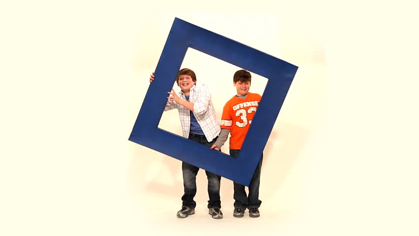  Two boys hold up a large frame and laugh.