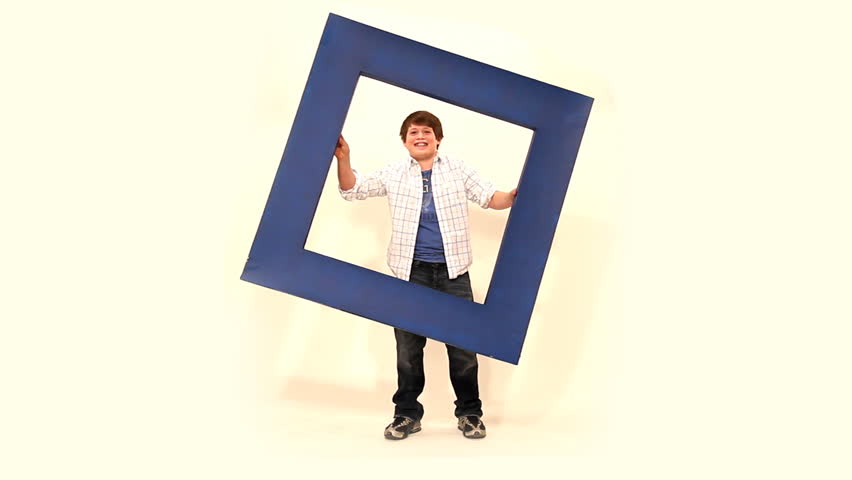 A young boy holds up a large frame.