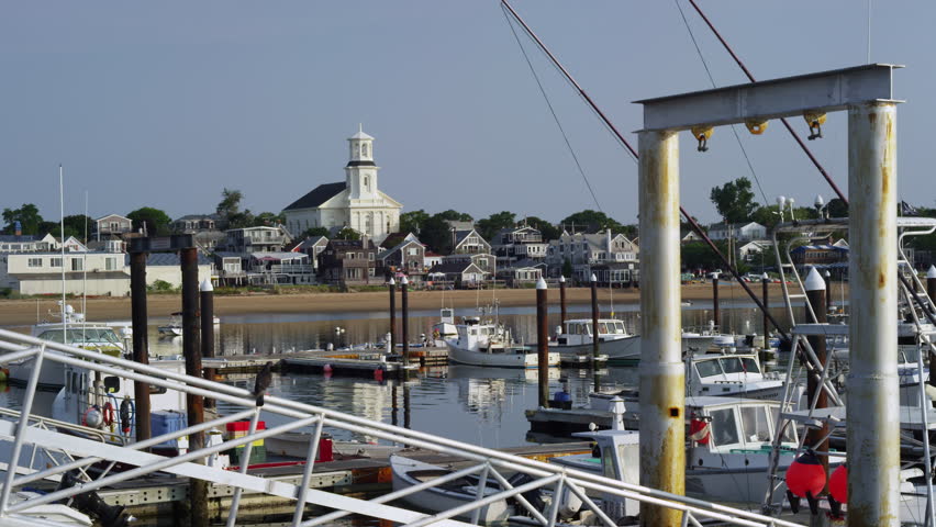 Cape Cod harbor with fishing boats, sky, pier, and town in background