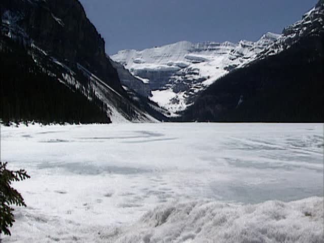Lake Louise in Rocky Mountains scenery - pan frozen glacial lake + snow pile. Banff National Park, Canada.