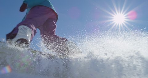 SLOW MOTION: Female snowboarder spraying snow into the camera