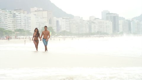 Loving couple run through the waves on a beach
