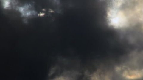 Sun's disk between move dark clouds on sky