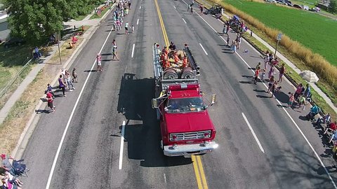 FOUNTAIN GREEN, UTAH - JUL 2014: Aerial fire truck parade kids getting candy. Small rural community annual celebration, family reunion festival. Homemade floats, tractors, high school bands.