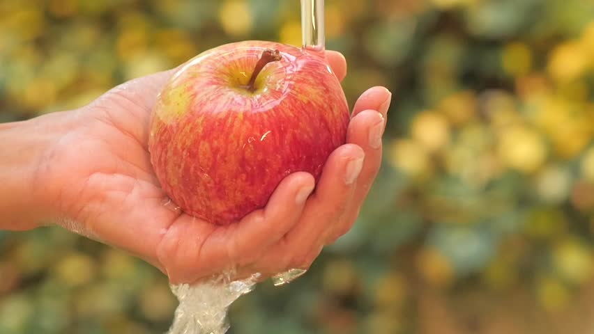 red apple in hand under flowing water slow motion 