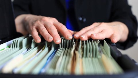 A close-up of a woman searching through a rather poor filing system.