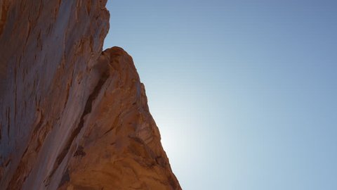 Slow motion wide tracking shot of man swinging from arch / Corona Arch, Moab, Utah, United States