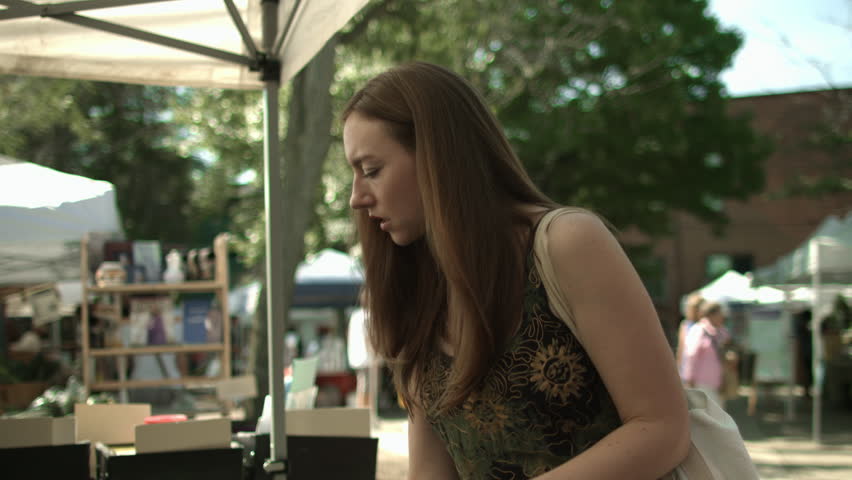 Young woman buying kale at open-air farmers