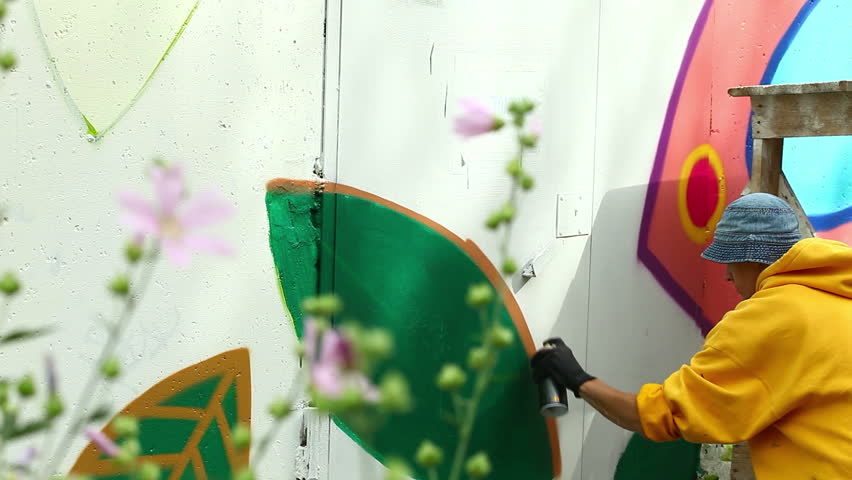 Creative guy paints picture on wall in park