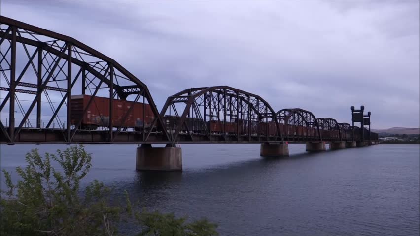 train slowly moving over bridge with gloomy gray sky