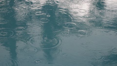 A puddle of water/pool of water with rain droplets creating circles in it