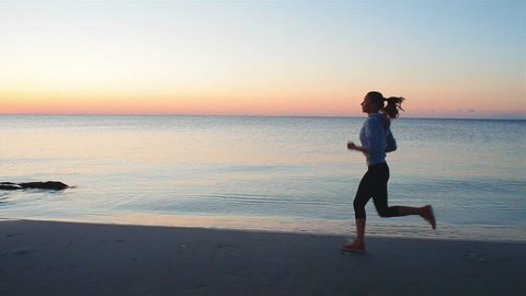 young woman with a slender figure is engaged in gymnastics at sea at sunrise. She makes a run along the sea coast. steadicam shot
