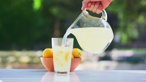 Fresh lemonade pouring into a glass outside Stockvideó
