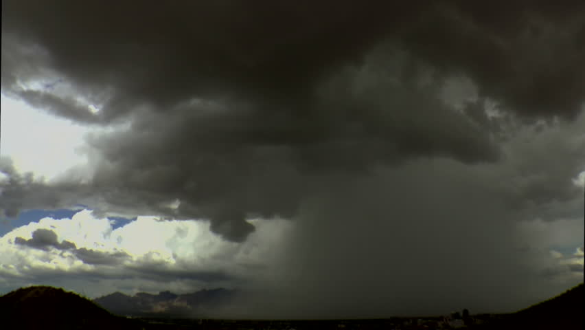 Time Lapse, Rain shafts, dark clouds, drop rain over foggy mountains when burst of sunlight highlights city of Tucson skyline during summer monsoon storm. 1080p
