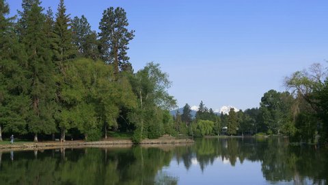Panning view of Mirror Pond in downtown Bend, Oregon, with snow-capped North and Middle Sister peaks in the background.