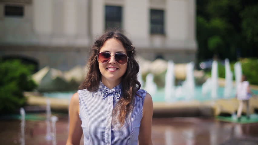 Woman smiling to the camera and taking off sunglasses
