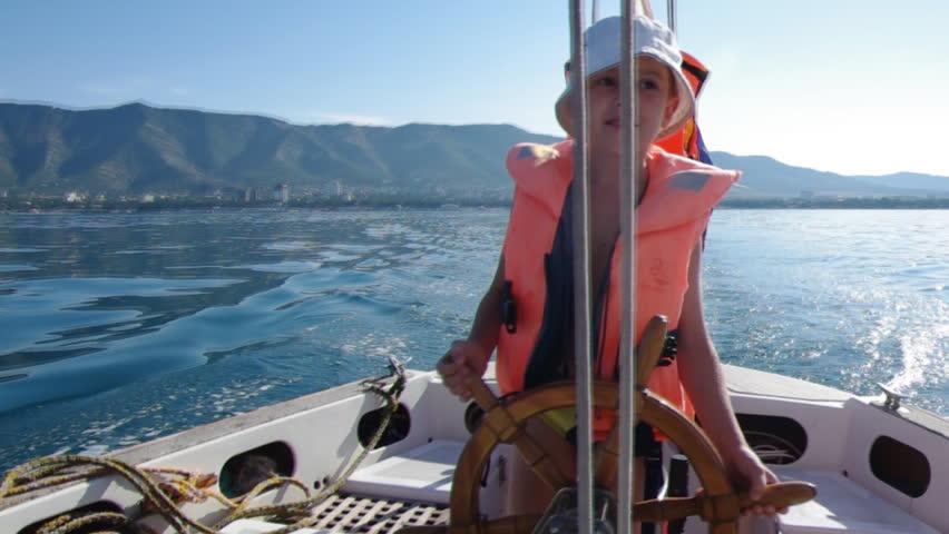 Cute little boy at sail boat wheel