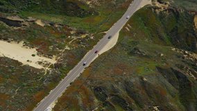 Aerial view of California Coastal road.  Helicopter flying along Big Sur coast near San Francisco with the Pacific ocean and State park mountain range.