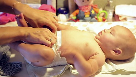 Mom changes the diaper of a small baby
