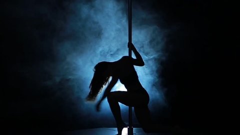 Silhouette of a sexy female pole dancing on blue background