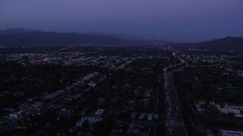 Aerial view of Los Angeles at Night. Helicopter shot flying over city business offices, suburban homes and streets at dusk.