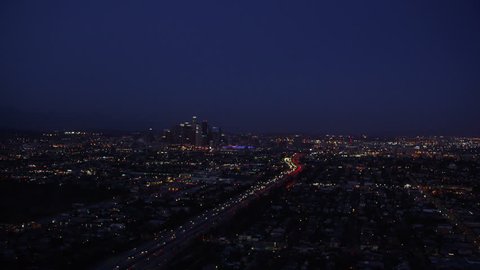 Aerial view of Los Angeles City, California at night. Helicopter shot over homes and business buildings in American suburbs.