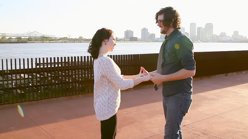 Couple dance in a park overlooking a bay