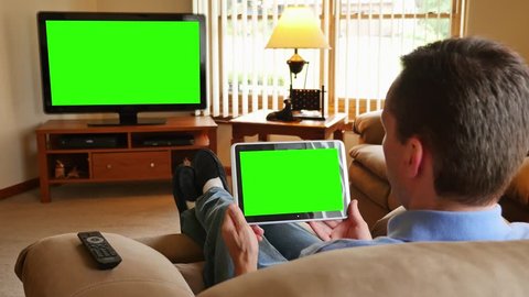A man watches television while holding a and tapping on a tablet device. Screens customizable with included optional luma matte and tracking points for advanced tracking.