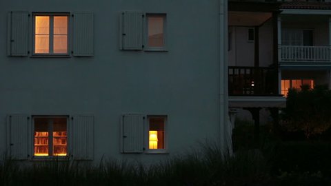 House and it's windows while light bulbs are on inside