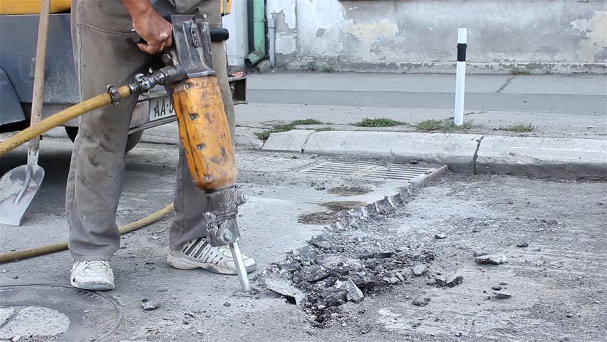 Worker drilling concrete with compressor on the street. Man with the drill breaking up asphalt on the road. Man using a jackhammer. Preparation for paving. Road work. Construction, vibration, close up Royalty-Free Stock Footage #7246792