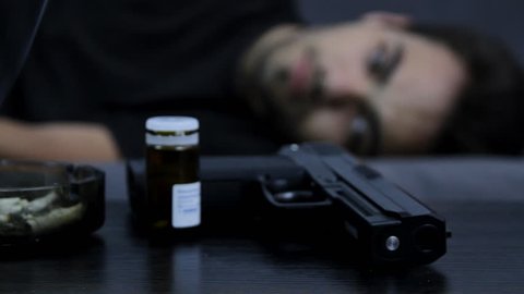 Young Man Laying In A Couch With Suicidal Thoughts, Gun, Pills, Rack Focus