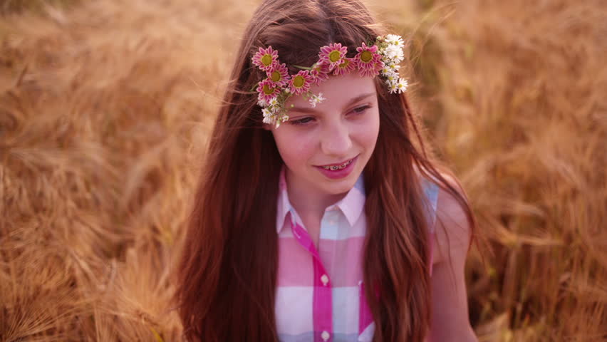 Young girl having a good time walking through wheat fields