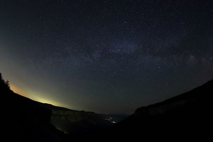 4K. Time lapse of the night sky with clouds and stars passing by behind mountain. Cave city Kachi-Kalon, Crimea, Russia. Ultra HD, 4096x2730

