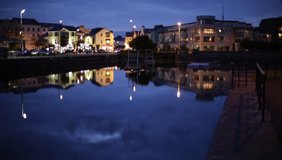 Night city with traffic and buildings reflections in the canal. Galway, Ireland.