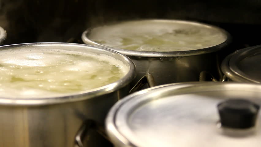 Pots cook on a stove in an industrial kitchen.