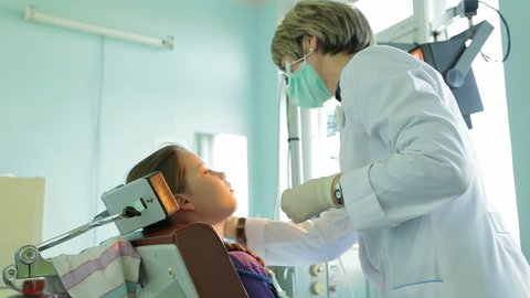 Shot of a pedodontist fitting braces for size in girl’s mouth.