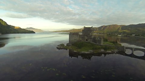 Two scenes of camera flying near serene beautiful Eilean Donan Castle near Isle of Skye in Scotland.