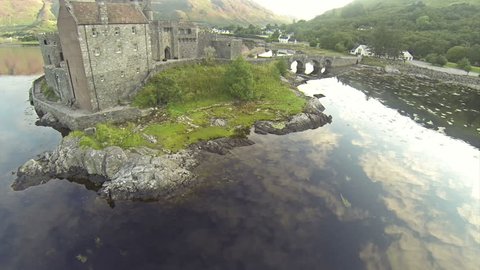 Two scenes of camera flying near serene beautiful Eilean Donan Castle near Isle of Skye in Scotland.