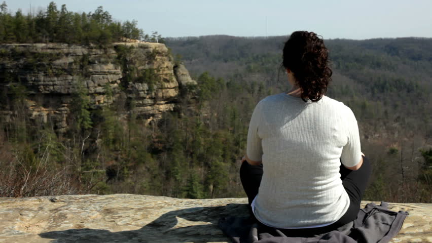 Girl sitting cross legged on Rock