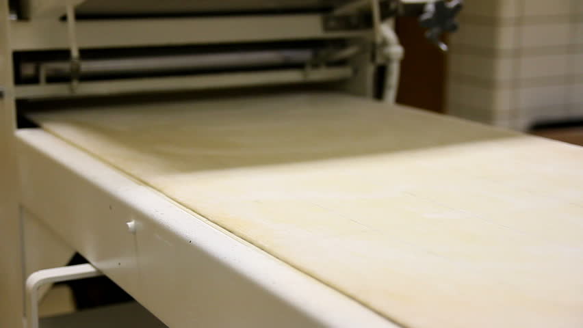 A machine flattens dough.
