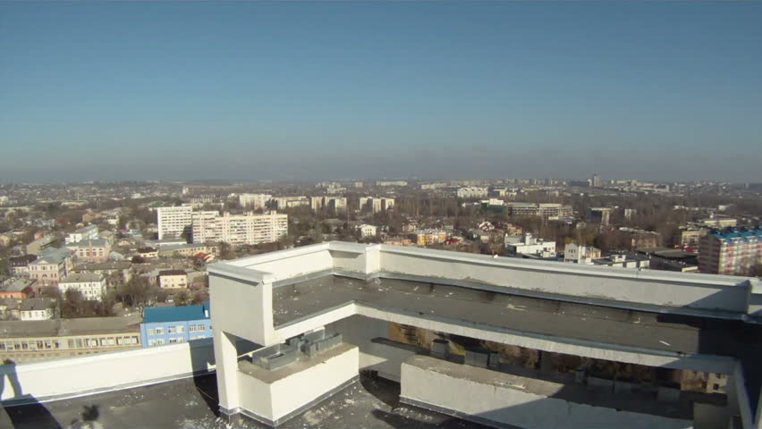 A man plays the guitar on the background of the panorama of the city. Beautiful kind from a house roof on a city panorama. Against a panorama of a city the man plays a guitar. Moving camera.