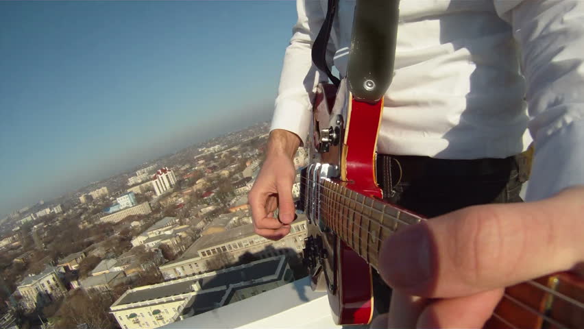 Hands of men play the guitar. A man plays the guitar on the background of the panorama of urban areas.
