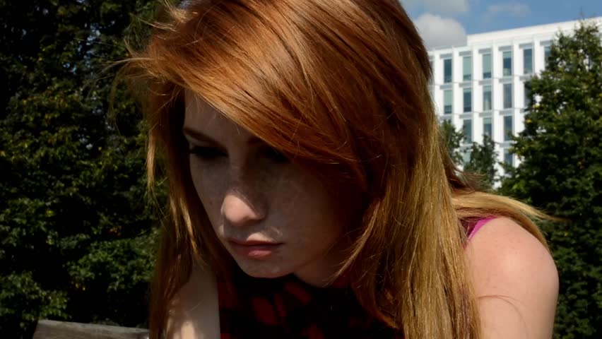 Young attractive woman sits on bench in the park - in her hand is crucifix (cross) - nature